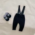 Infant black ribbed overall trousers set with matching baby sneakers on textured background - Black