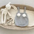 Vue détaillée d'un body en tricot gris pour bébé avec pompons blancs et boutons-pression - 90 / Gris Clair