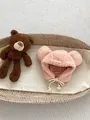 Close-up of pink polar fleece baby hat with bear ears and braided tassels in a basket - One Size / Earflap Hat / Pink