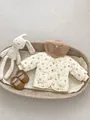 Gevoerd babyvestje met bloemenprint in crèmewit voorzien van knopen en zakken - 66cm / Bloemenpatroon