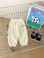 Close-up of off-white waffle knit toddler pants with smiley face embroidery in a cart - 120cm / Apricot