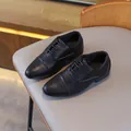 Classic black boys' cap-toe dress shoes with lace-up closure on a grey chair - EU 26 / Black