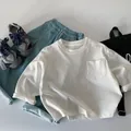 Dettaglio in piano di maglietta bianca a maniche lunghe in cotone e pantaloni verde acqua - 90cm / Bianco