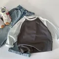 Vista piatta di una maglietta raglan a maniche lunghe da bambino con jeans e scarpe - 90cm / Grigio