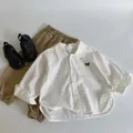 Flat lay of a white long-sleeve cotton shirt with cat embroidery and khaki casual pants - 90 / White (Cat Embroidery)