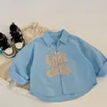 Flat lay detail of light blue toddler shirt with cute elephant print and beige trousers - 90cm / Blue