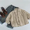 Dettaglio camicia a righe da bambino con trama in cotone ed etichetta taglia 90 - 90cm / Rigato Albicocca