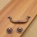 Antique red copper drawer handle set with ornate classical patterns on wooden background - Hole Distance 64mm / Red Bronze
