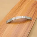 Close-up of modern silver curved cabinet handle on wooden surface with brushed finish - 5015 Brushed-96mm