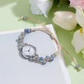Dettaglio dell'orologio bracciale intrecciato con perline blu e cassa argento su fiori - Perline Blu Cinturino Caffè Chiaro Quadrante Bianco