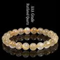 AAA Grade Rutilated Quartz bracelet with 10mm golden needle beads on black background - Grade AAA