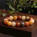 Natural Jinsiyu bead bracelet with multi-color polished jadeite stones on a wooden background - Round Bead Style