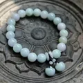 Macro shot of natural green jadeite beads and mini apple pendants on a carved stone plate - Double Apple