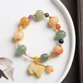 Macro detail of pumpkin-shaped jade beads with a carved rabbit charm on a beaded bracelet - Pumpkin Bead Bell With Pixiu
