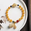 Macro view of Chinese yellow jade bead bracelet with enamel flower and gourd charms - All Yellow Round Bead With Gourd