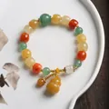 Detail of colorful gemstone beads with yellow gourd pendant on a ceramic dish - Yellow Green Barrel Bead With Gourd