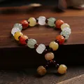 Handcrafted silk jade pumpkin bead bracelet with garnet accents on a vintage wood surface - Small Pumpkin Bead Tassel