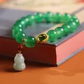 Green agate bead bracelet with golden vintage gourd pendant on a decorative book - Green Agate Gold Plated Jadeite Gourd