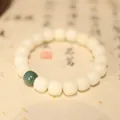 Detail van witte Bodhi-gebedskralen met één groene kraal op kalligrafiepapier - Yin Huid Bodhi Stijl
