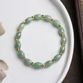 Natural green jade bead bracelet with faceted gold metal accents on a white plate - Small Rice Bead