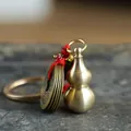 Brass gourd with five emperor coins keychain pendant on textured grey stone background - Small Hollow Brass Gourd with Wu Di Coins (HTYS18)