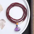 Detail of triple-layer garnet bracelet with amethyst shell pendant on white ceramic plate - Three-Strand Garnet with Amethyst Shell