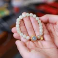 Detail of natural jadeite and aquamarine beaded bracelet with gold lock pendant in hand - Aquamarine Ruyi Design Style