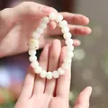 Detail of white Bodhi seed bracelet with a carved cat paw bead held by hands - Charred Cat Paw Kitten Style
