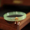 Primer plano detallado de pulseras de jade verde con colgante de loto dorado y perlas blancas - Verde Manzana