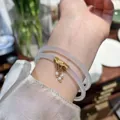 Detalle de pulsera doble de calcedonia lavanda con dije de loto dorado y perlas - Estilo Hilo Dorado / Blanco