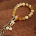 Detail of candy-colored Bodhi seed bracelet with a cute white cat charm and woven cord - Burnt White Jade Bodhi (Bear Claw)