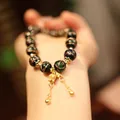 Ethnic style glass bead bracelet with gold accents and tassel charms on a person's wrist - Blue Green Glaze Lily Of The Valley Style