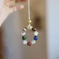 Nahaufnahme bunter Glasperlen mit goldener Filigran-Hohlkugel und funkelnden Kristallringen - Klein