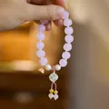 Detailed shot of pink lotus beads with pearl accents and a delicate woven tassel - Rouge Snow Pink Glazed Glass Lotus Flower Ball Bracelet