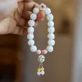 Detail of beaded bracelet featuring white lily of the valley flowers and pink cords - Porcelain White Glazed Glass Lotus Hand-painted Beads