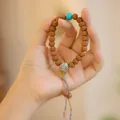 Pulsera natural Rudraksha Bodhi con cuenta turquesa y detalle de cabeza de Buda plata - Colgante Rudraksha con Borla (MNSL16-01)