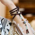Detail of red sandalwood 108 beads bracelet with lacquer decor on female wrist - 6mm 108 Beads / Dark Reddish Brown - Blue Lacquer Bead Style