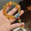 Chinese style purple and gold glass beaded bracelet with blue tassels on wrist - Warm Gold Glazed Glass Lotus Bracelet