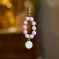 Close-up of a spiritual phone charm with pink beads, gold accents and Buddha eye pendant - Pink Incense Ash Porcelain - White Wealth God