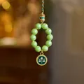 Close-up of green beads with ancient gold finish charm and divine eye pendant - Green Incense Ash Porcelain - Green Wealth God