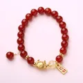 Red agate bead bracelet with golden dragon charm and lucky tag on pink surface - Luck Dumpling Dragon Style / Red