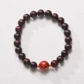 Close-up of red cinnabar bead and dark wood sandalwood prayer beads with golden accents - Red Lacquer Bead Sandalwood