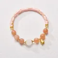 Detail of sunstone bead bracelet featuring pink enamel cuff and golden bell charm - Pink Lily Of The Valley Style