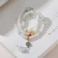 Detailed shot of multi-layer jadeite beaded bracelet with enamel lotus charm on book - Tianshan Jade Flower Wreath Tassel 1