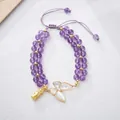 Détail d'un bracelet en perles d'améthyste avec breloque papillon et accents dorés - Style Papillon Améthyste / Améthyste Violet