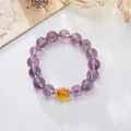 Detailed shot of amethyst beaded bracelet with yellow citrine bead and gold accents - 12mm Lavender Jade Yellow Citrine Fortune Style