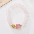 Close-up of pink quartz beads with a gold hollow ball and purple fluorite charm - Rose Quartz Fluorite Lion Auspicious Cloud Ball Style