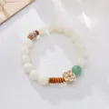 White Bodhi seed bracelet with green aventurine flower pendant on white textured background - Green Aventurine Plum Blossom Style