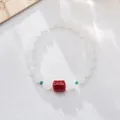 Detailed view of white jade beads with cinnabar mantra barrel and turquoise spacers - Medium Bead Style