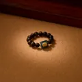 Detailed macro view of an agarwood bead ring featuring green jade and golden relief - Agarwood 925 Silver Blue Water Jadeite Style